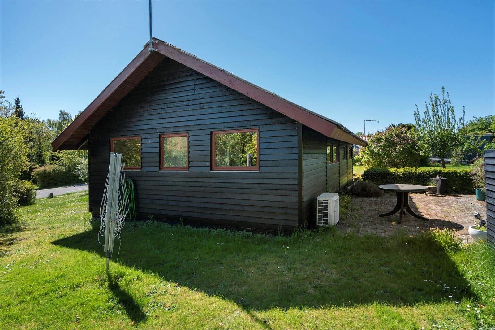 Wooden house with garden, terrace, and table. Outdoor area with lawn and trees.