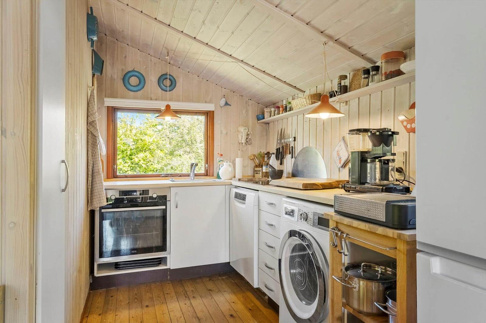 Kitchen with wooden walls, window, sink, stove, and washing machine.