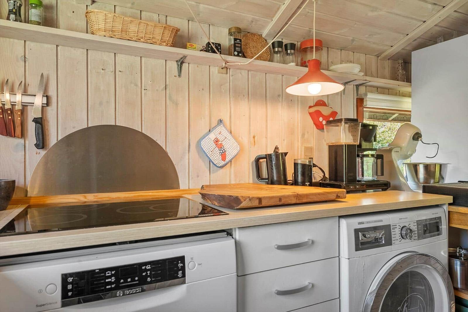 Kitchen with wooden countertop, induction cooktop, dishwasher, and washing machine