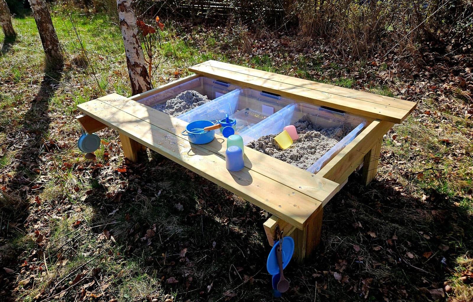 Holz-Sandkasten mit Spielzeug im Freien