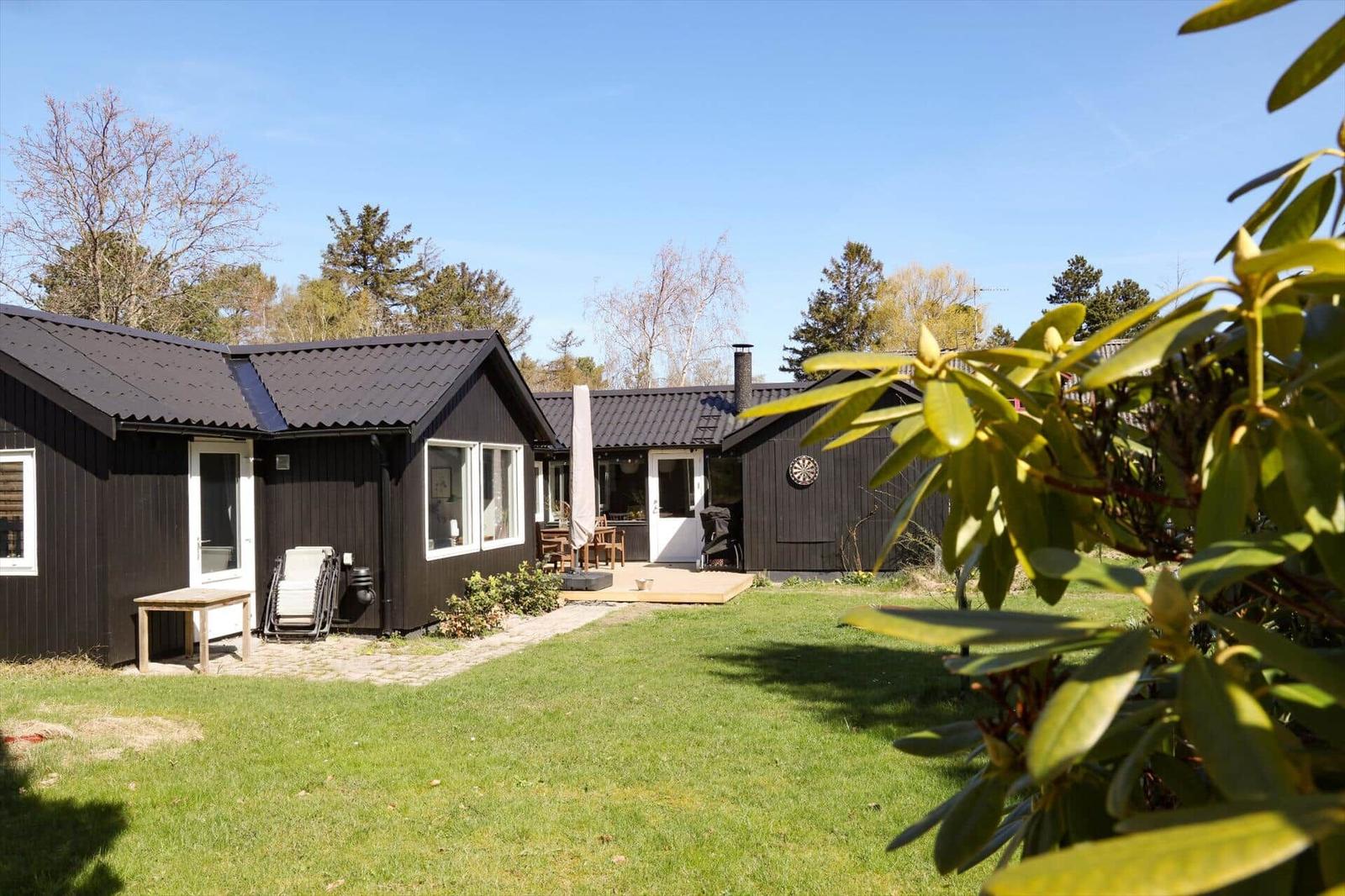Schwarze Holzhäuser mit Terrasse und Garten. Blick auf die Umgebung.