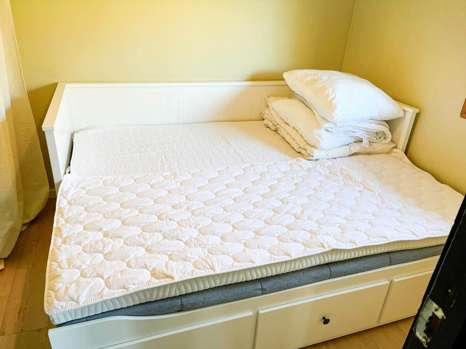 Ein Bett mit Matratze und Bettwäsche in einem Raum mit gelben Wänden.