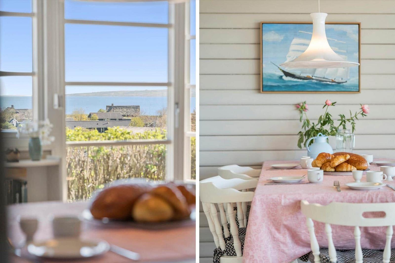 Tisch mit Frühstück und Blick aufs Meer. Wandbild mit Segelschiff.