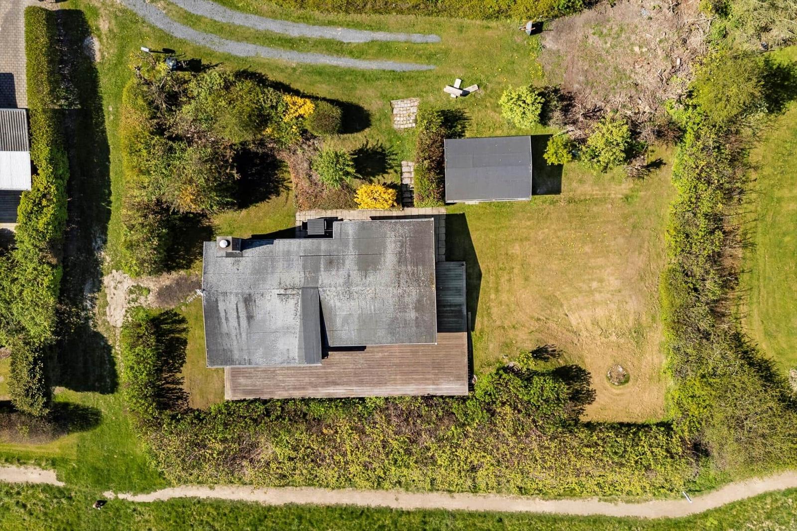 Haus mit Garten und Nebengebäude, umgeben von Grünflächen und Hecken.