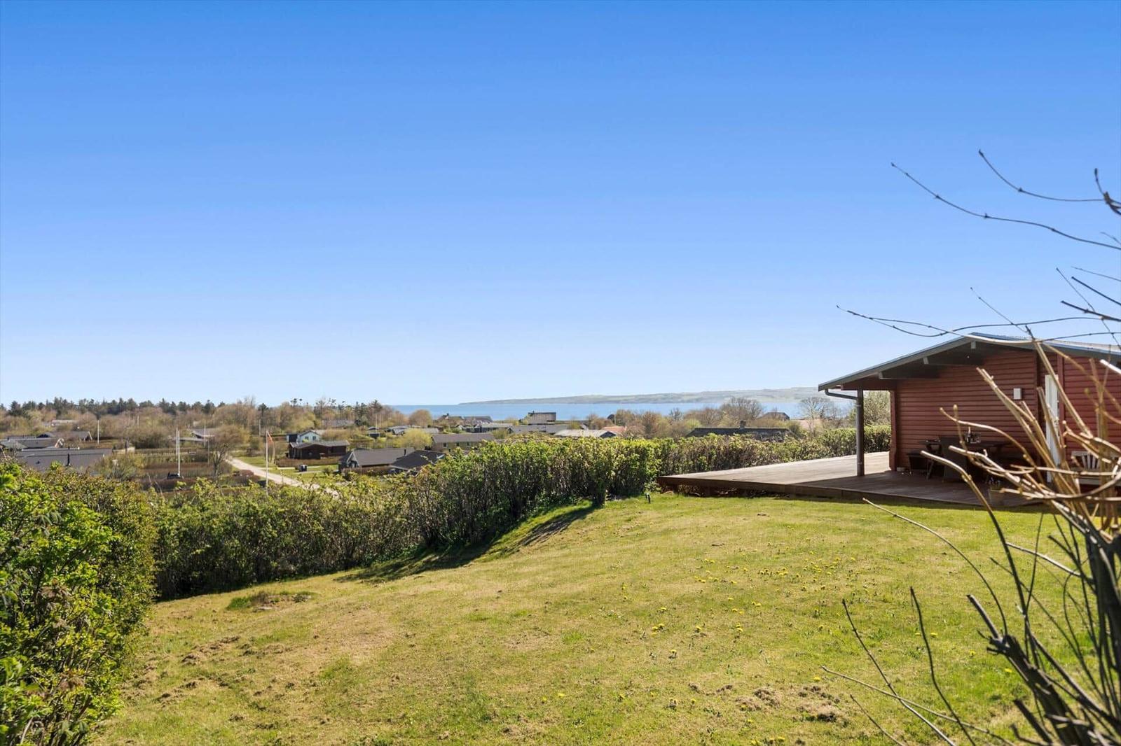 Haus mit Terrasse, Grünfläche und Blick auf Wasser und Dorf.