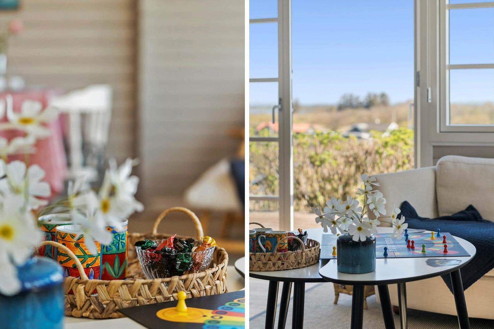 Tisch mit Spiel und Blumen vor Fenster mit Blick auf Landschaft