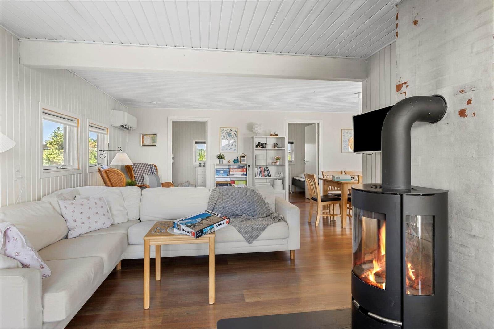 Wohnzimmer mit Sofa, Kamin und Essbereich im Hintergrund.