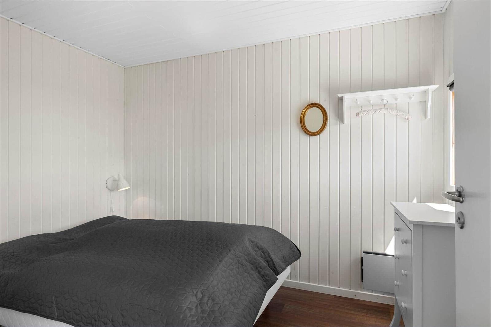 Schlafzimmer mit Bett, Wandspiegel und Kleiderschrank.