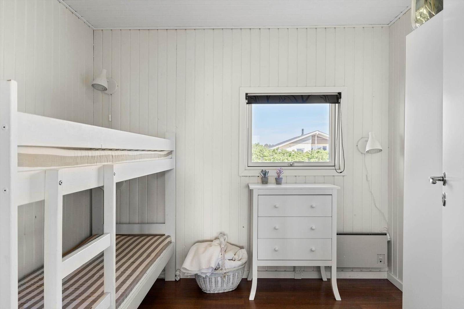 Zimmer mit Doppelstockbett, Schrank und Fenster mit Blick auf Haus.