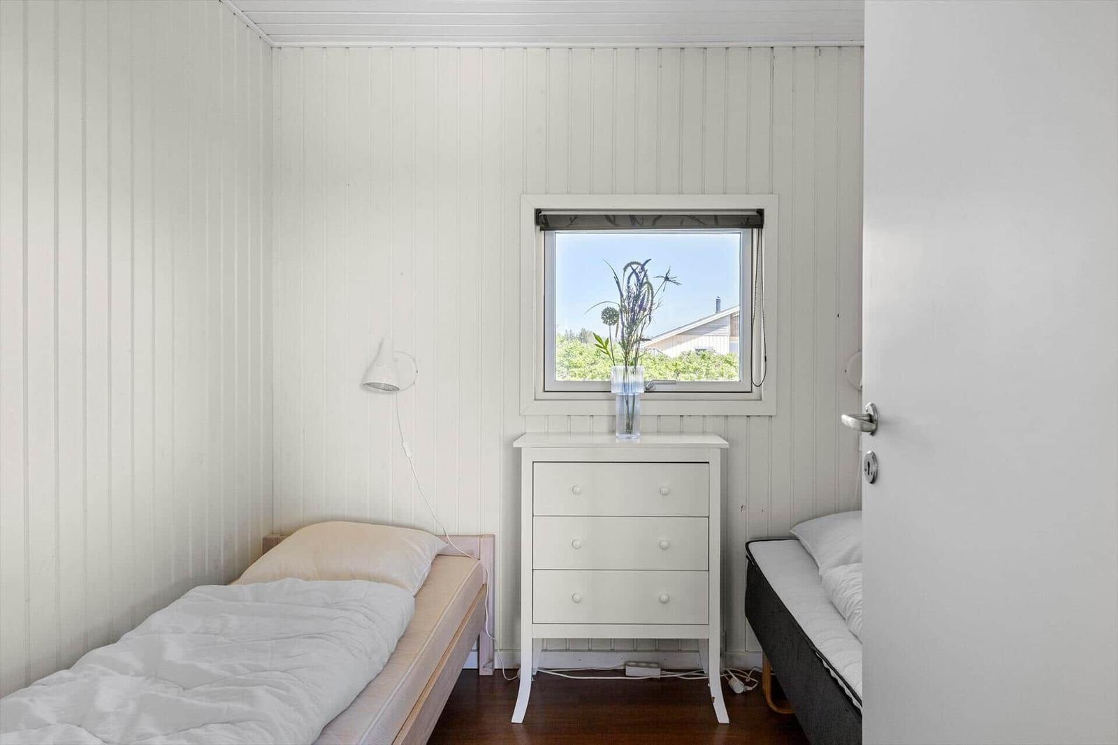 Zimmer mit zwei Betten, Schrank und Fenster mit Blick auf Grün.