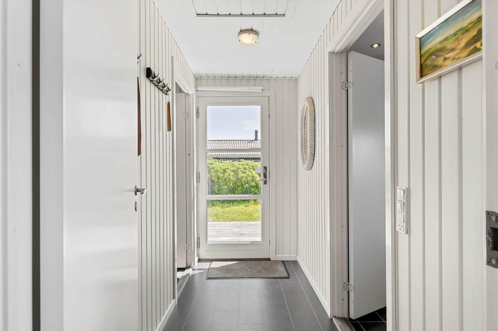 Hausflur mit weißem Holzverkleidung und Tür zum Außenbereich.
