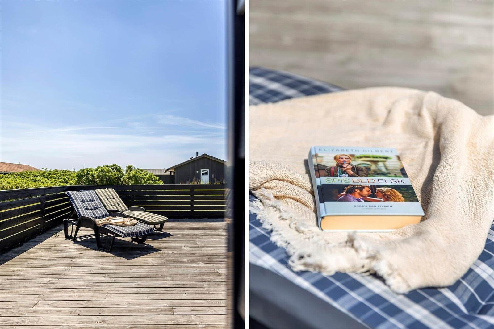 Terrasse mit Liegestühlen und Blick auf die Landschaft. Buch auf Decken mit Plaidmuster.