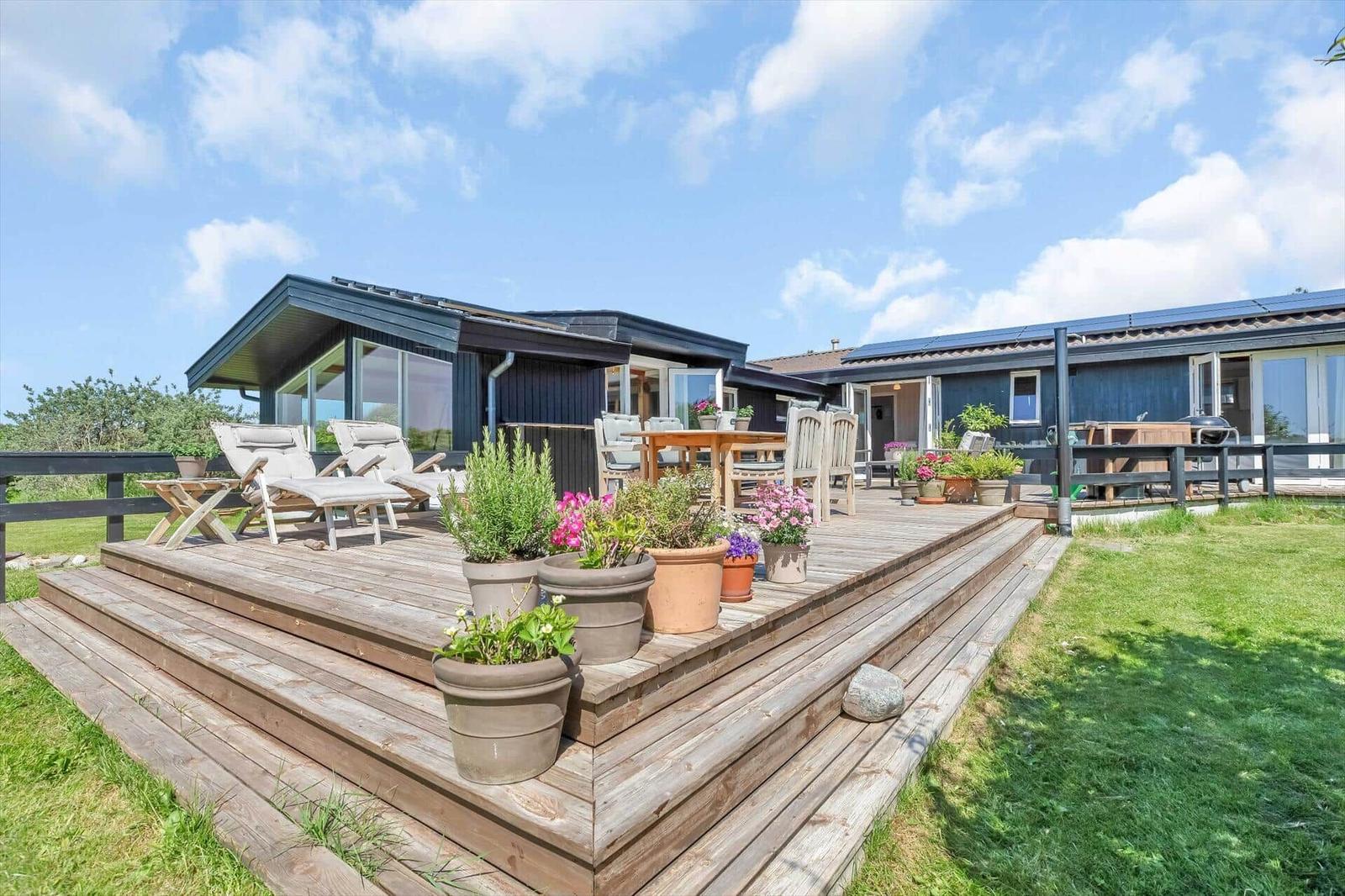 Terrasse mit Gartenmöbeln, Pflanzen und Blick auf das Haus.