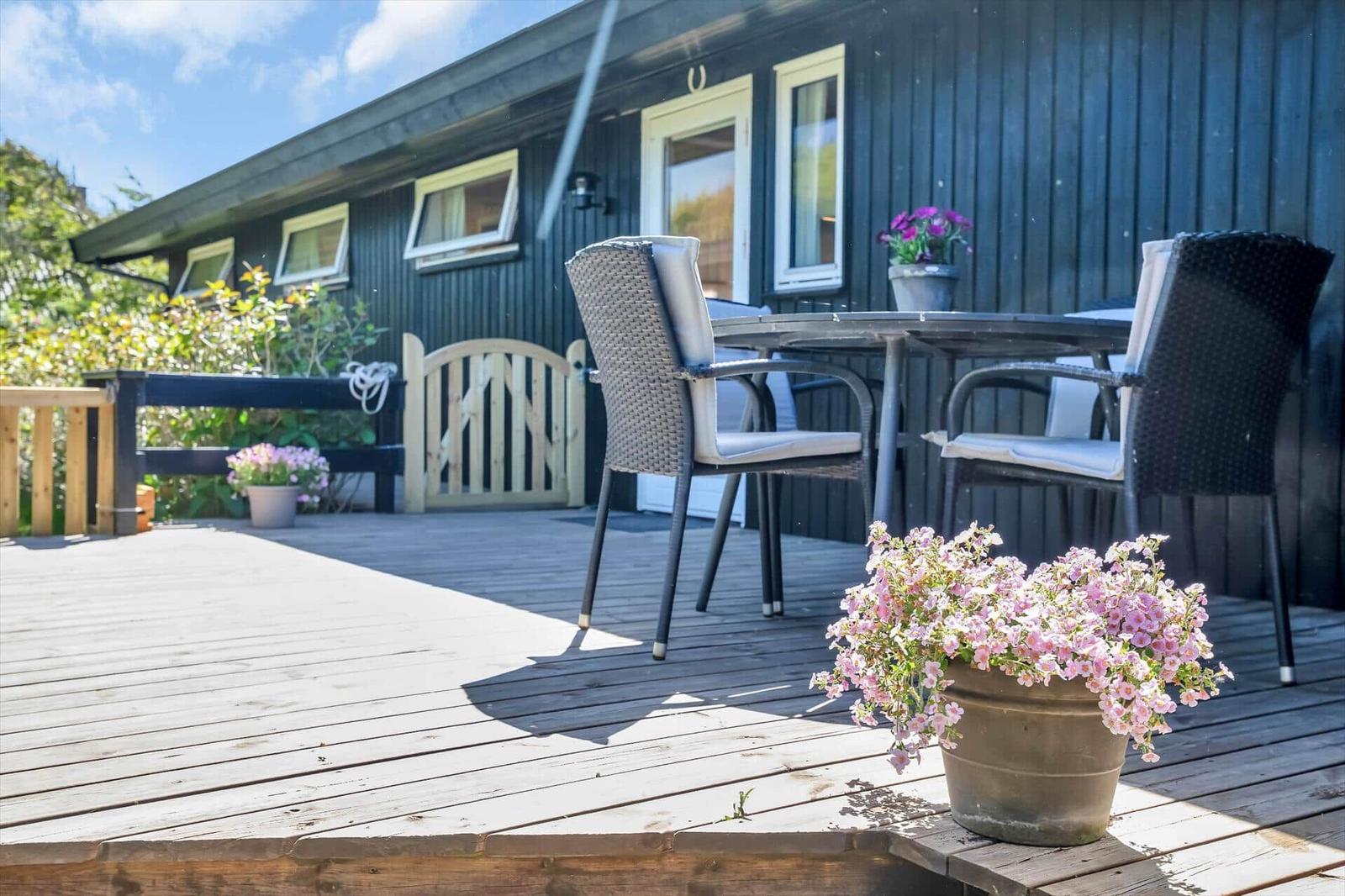 Terrasse mit Tisch, Stühlen und Blumen vor einem Holzhaus.