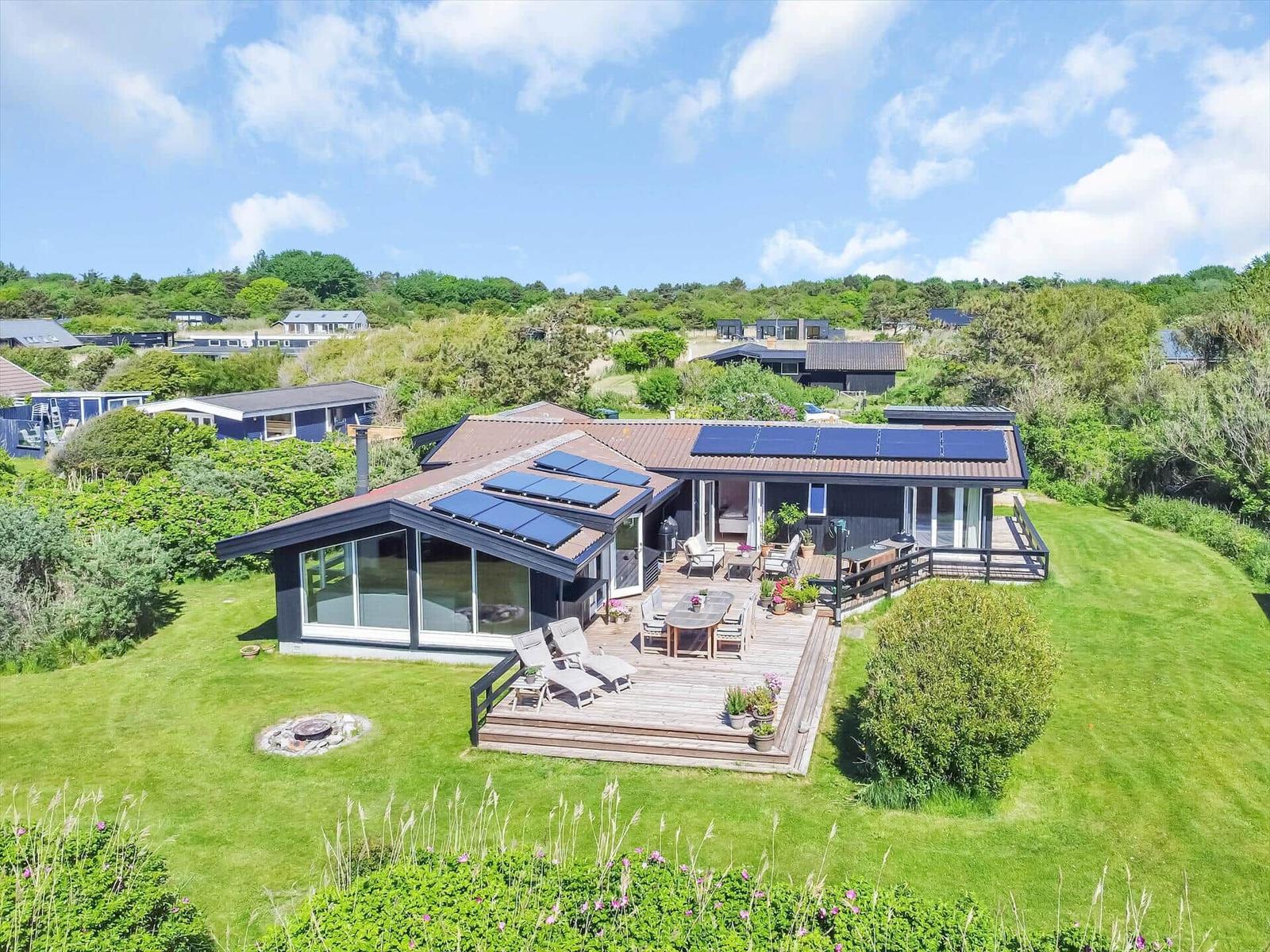Modernes Haus mit Solaranlage, Terrasse und Garten. Blick auf grüne Landschaft.