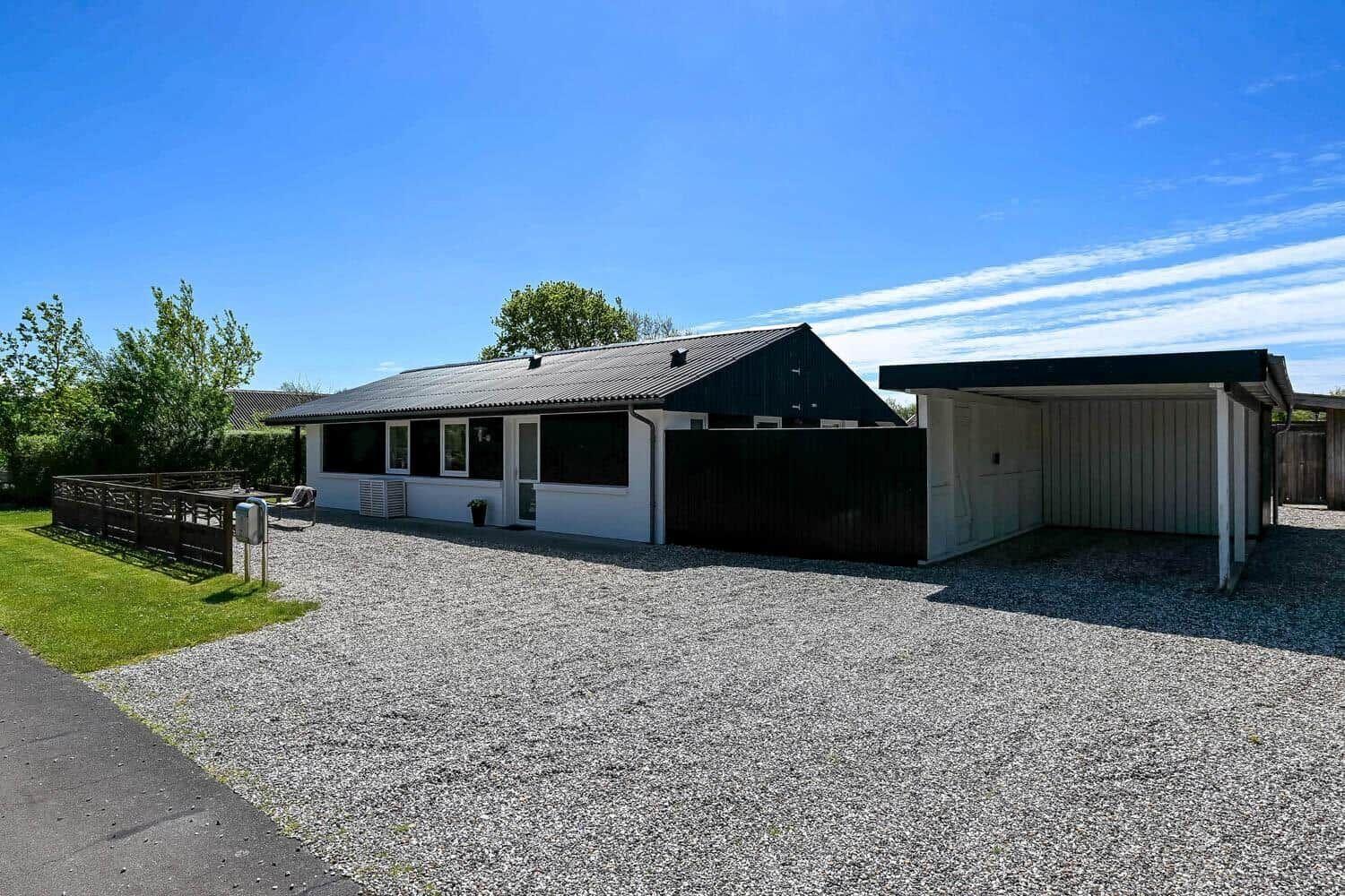 Ein Haus mit Garage und Kiesfläche unter blauem Himmel.