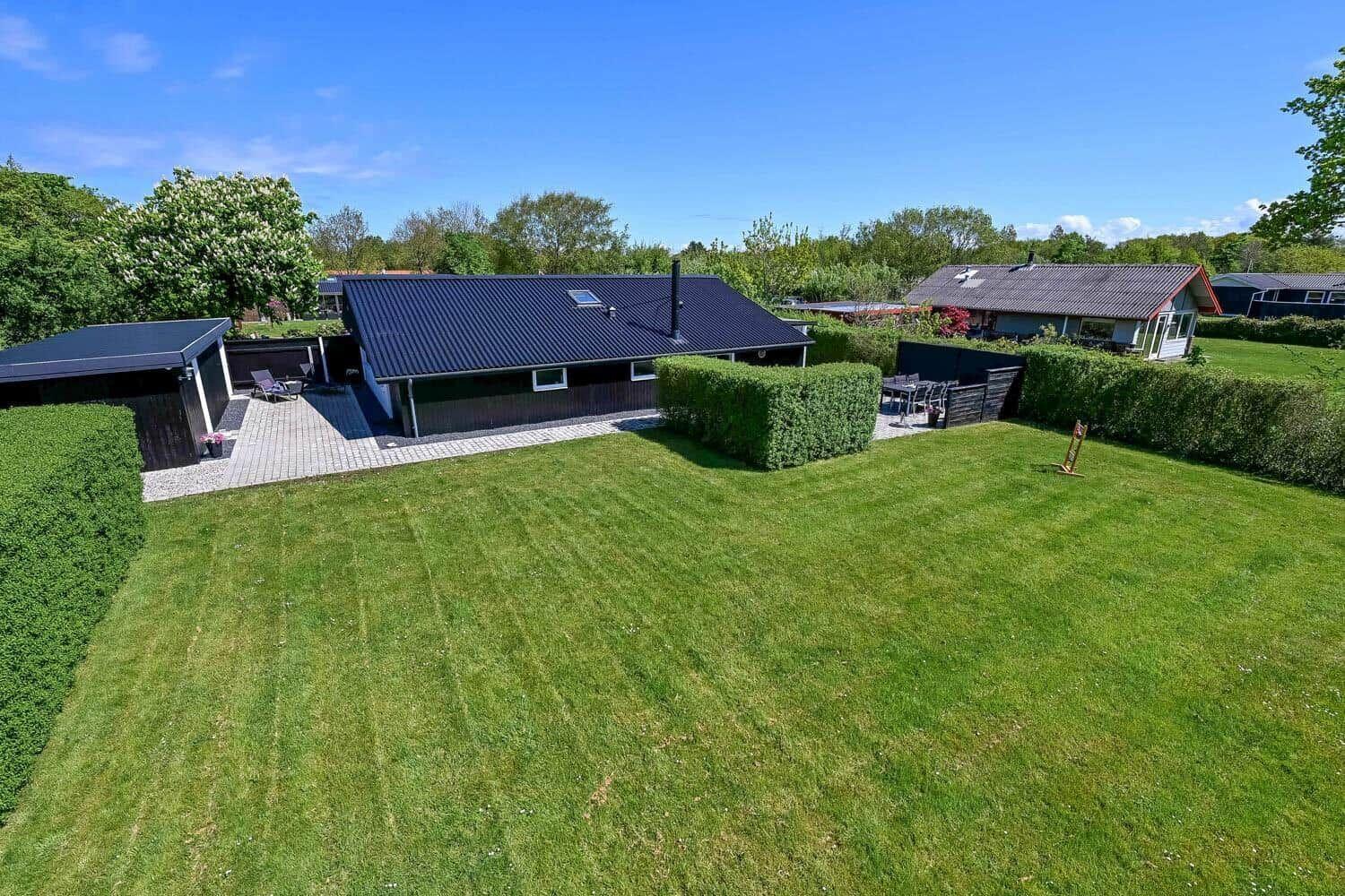 Haus mit Garten, Terrasse und Grillplatz. Grünfläche und Hecken umgeben das Anwesen.