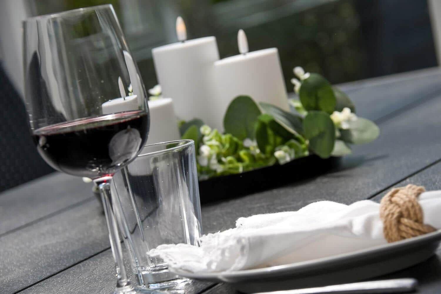 Ein Tisch mit Wein, Kerzen und einer Servierplatte mit Tischdecke.