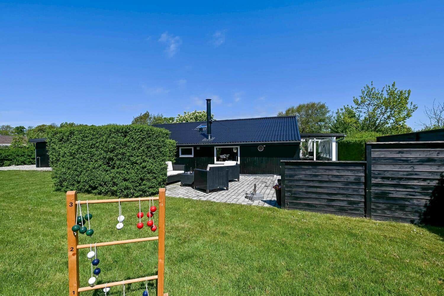 Ein Haus mit Terrasse und Garten. Im Vordergrund steht ein Boule-Spielgerät.