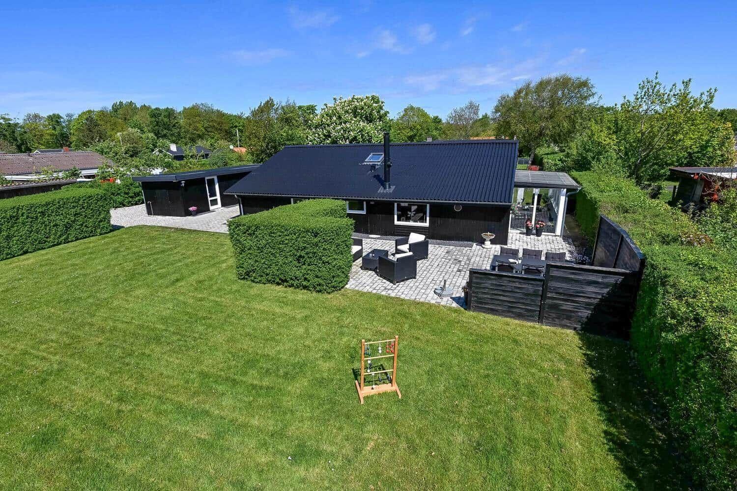 Moderne Villa mit großem Garten und Terrasse mit Gartenmöbeln.