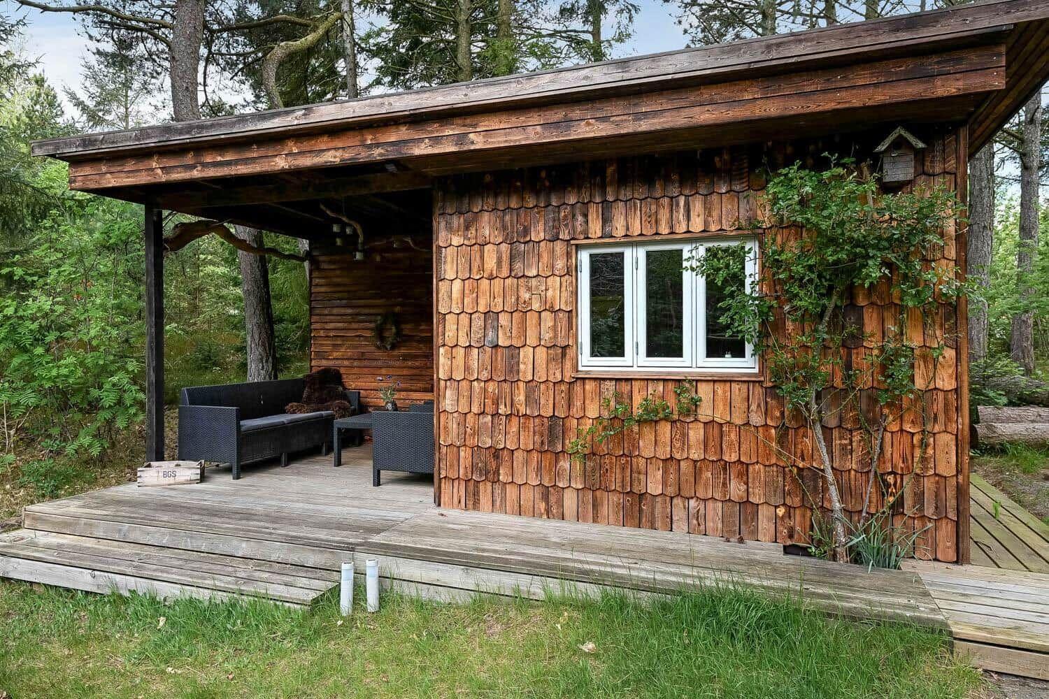 Holzhütte mit Terrasse und Sitzgelegenheit im Wald