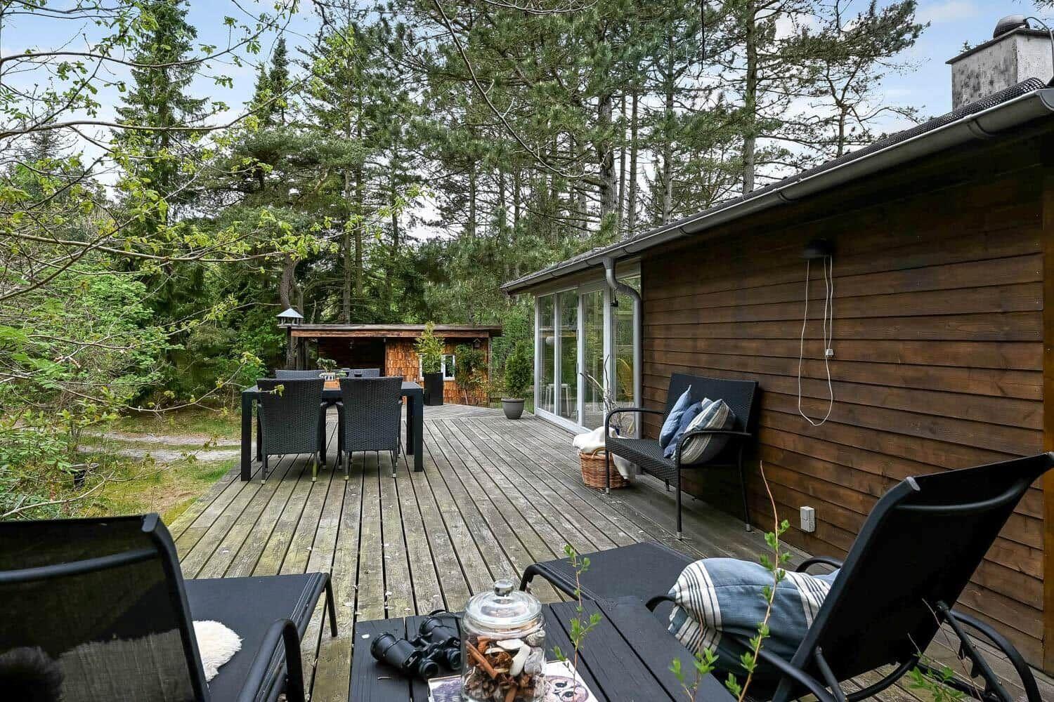 Holzterrasse mit Sitzgelegenheiten und Blick in den Wald.