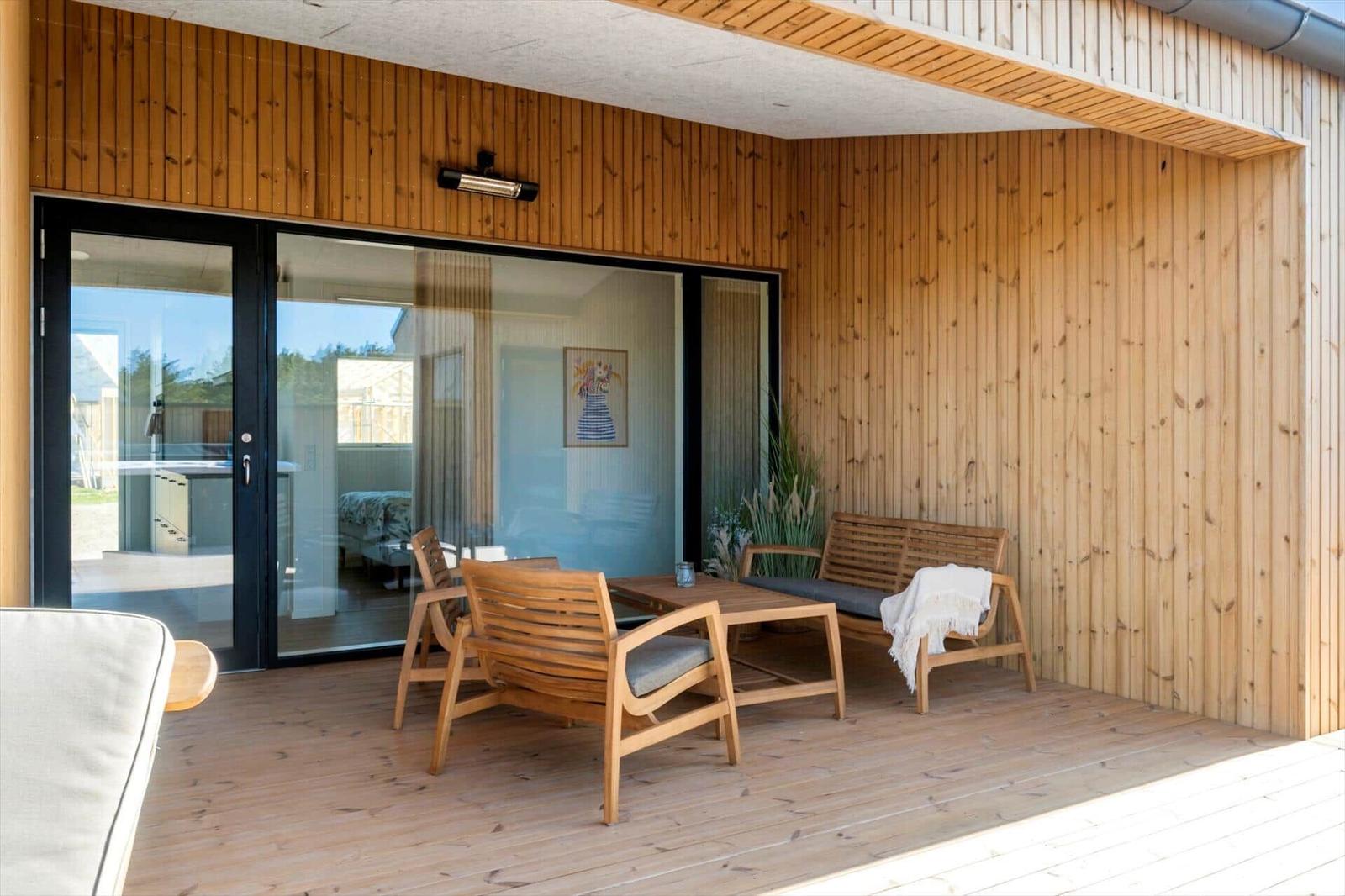 Terrasse mit Holzwand, Sitzgruppe und Glastür zum Innenraum.