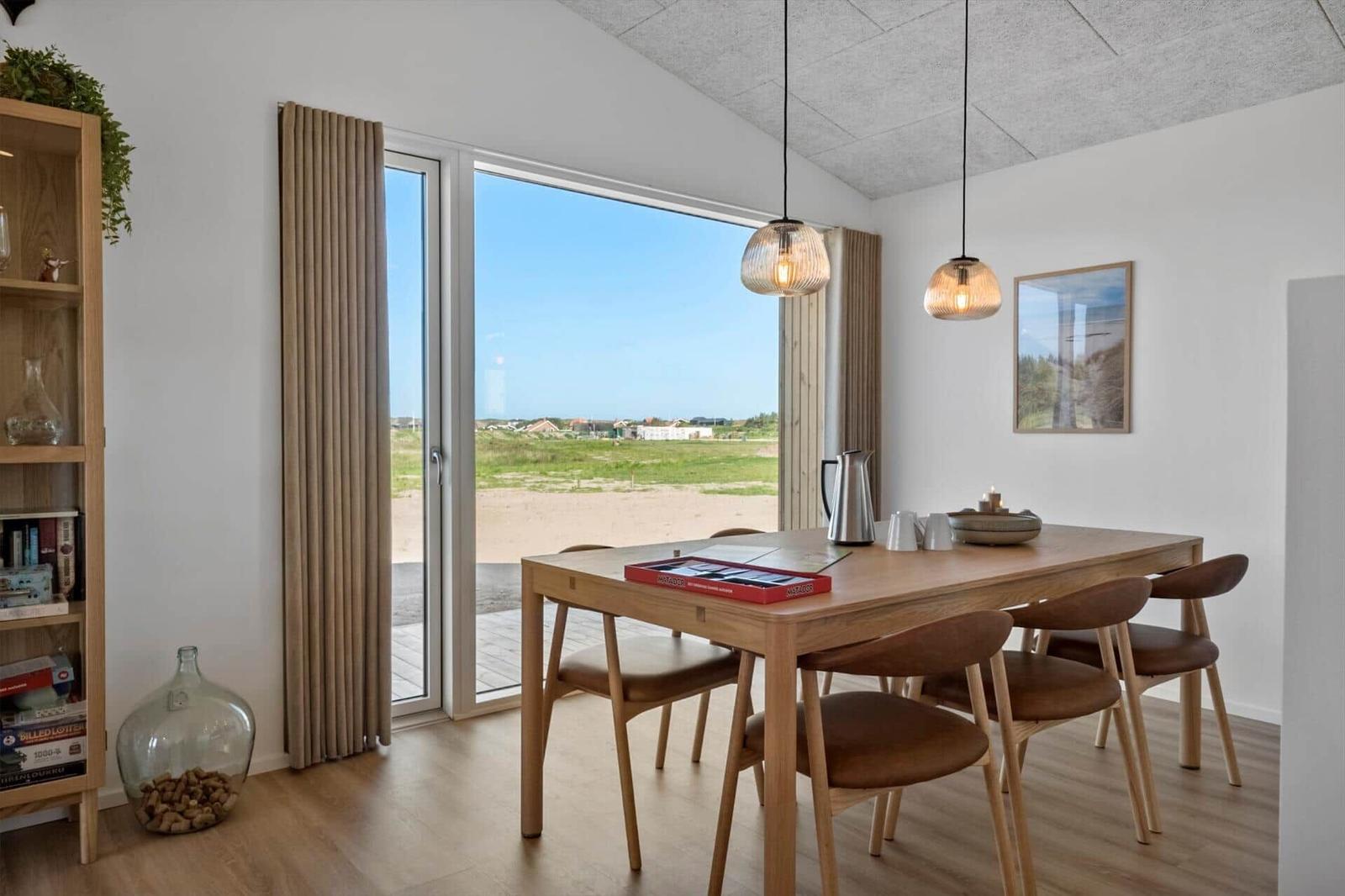 Esszimmer mit Holztisch, Stühlen und Blick auf Strand