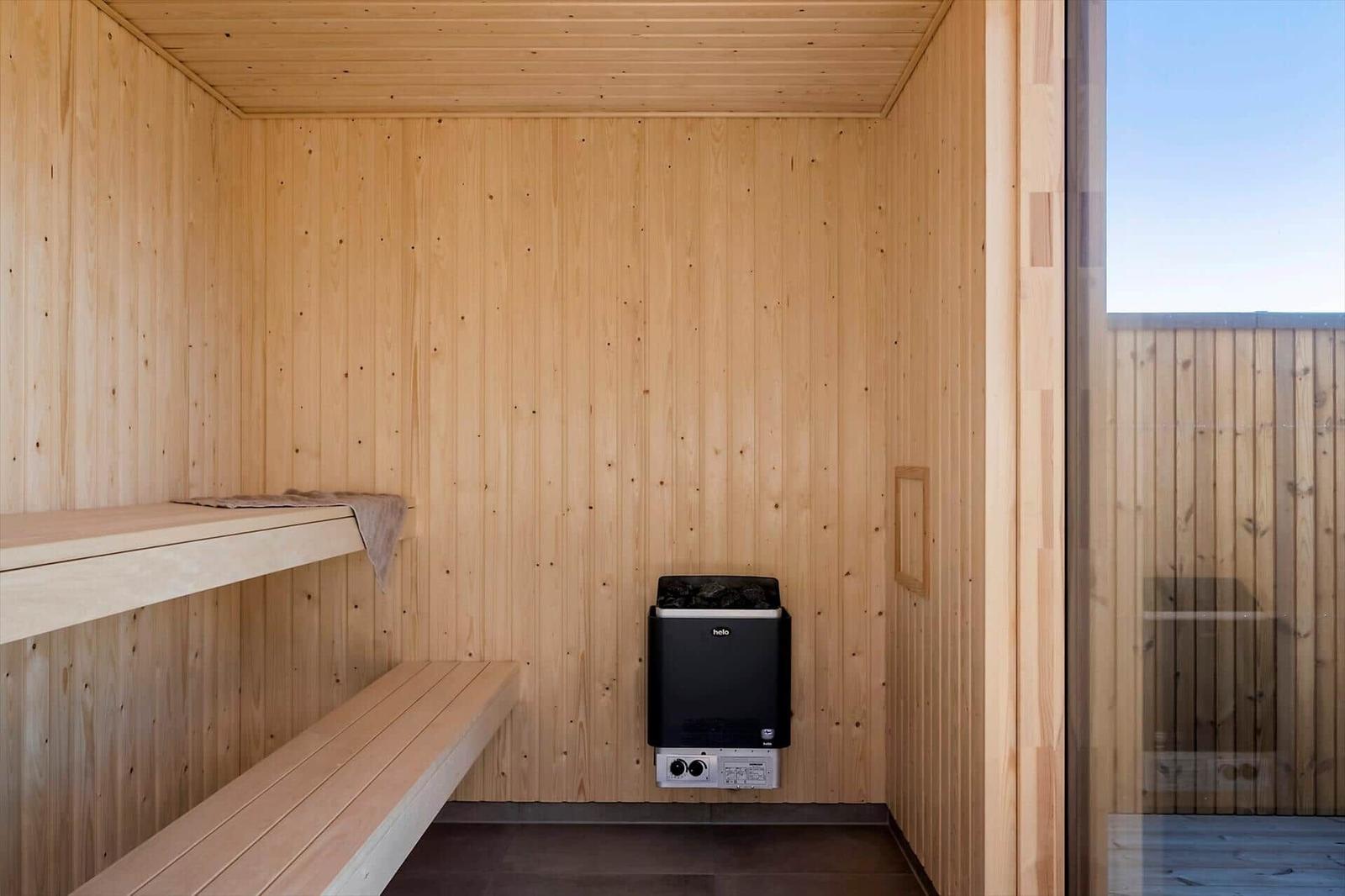 Sauna mit Holzwand, Sitzbänken und Heizgerät.
