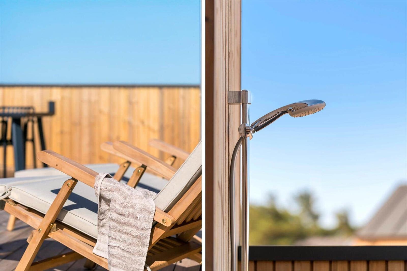 Terrasse mit Liegestühlen und Duschbereich mit Duschkopf.