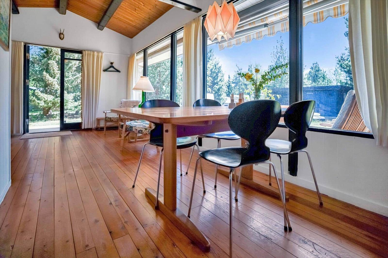 Esszimmer mit Holzboden, Tisch und Stühlen, großes Fenster mit Blick auf Garten
