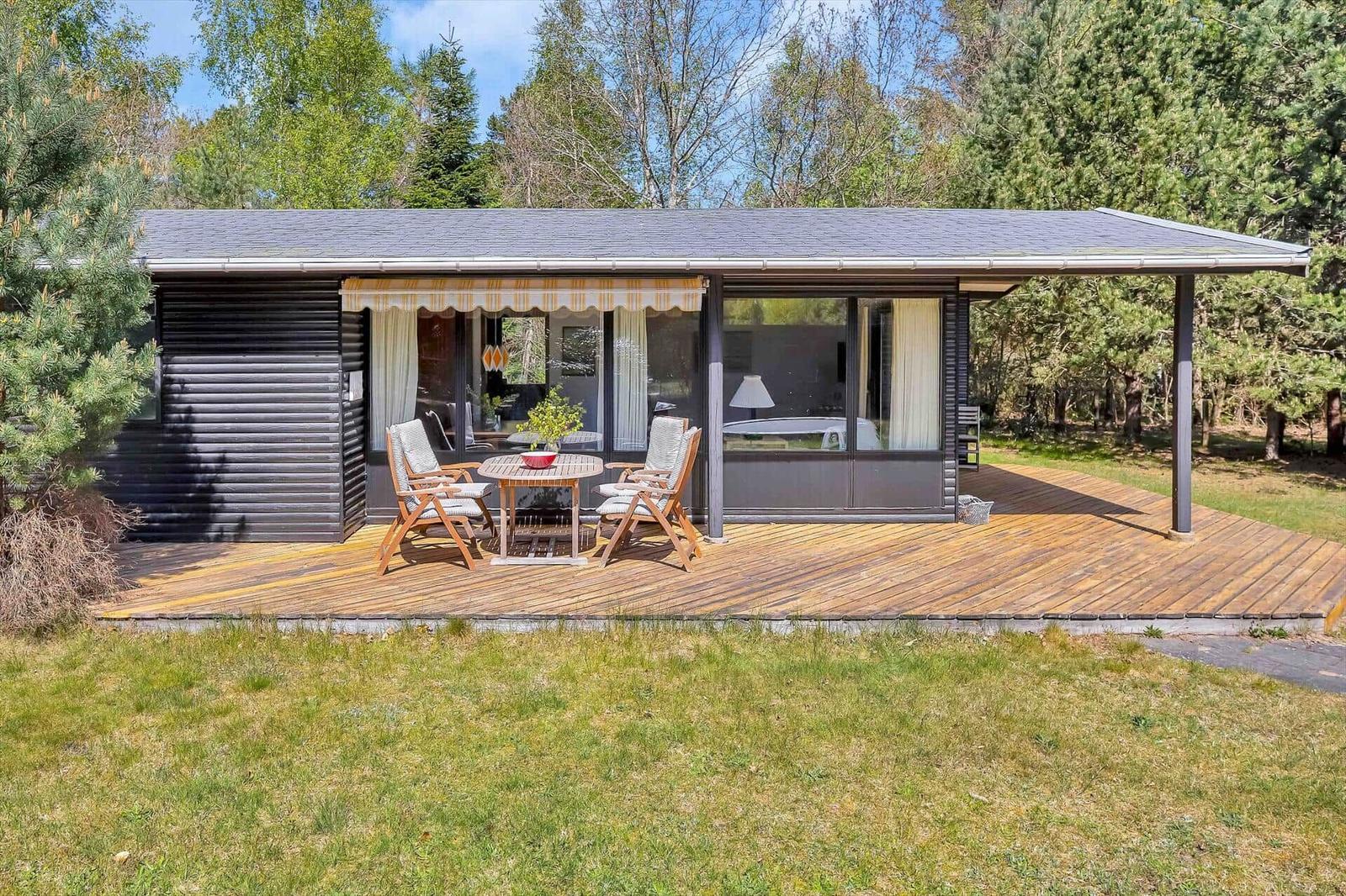 Moderne Holzhütte mit Terrasse und Garten. Sicht auf Wohnbereich und Schlafzimmer.