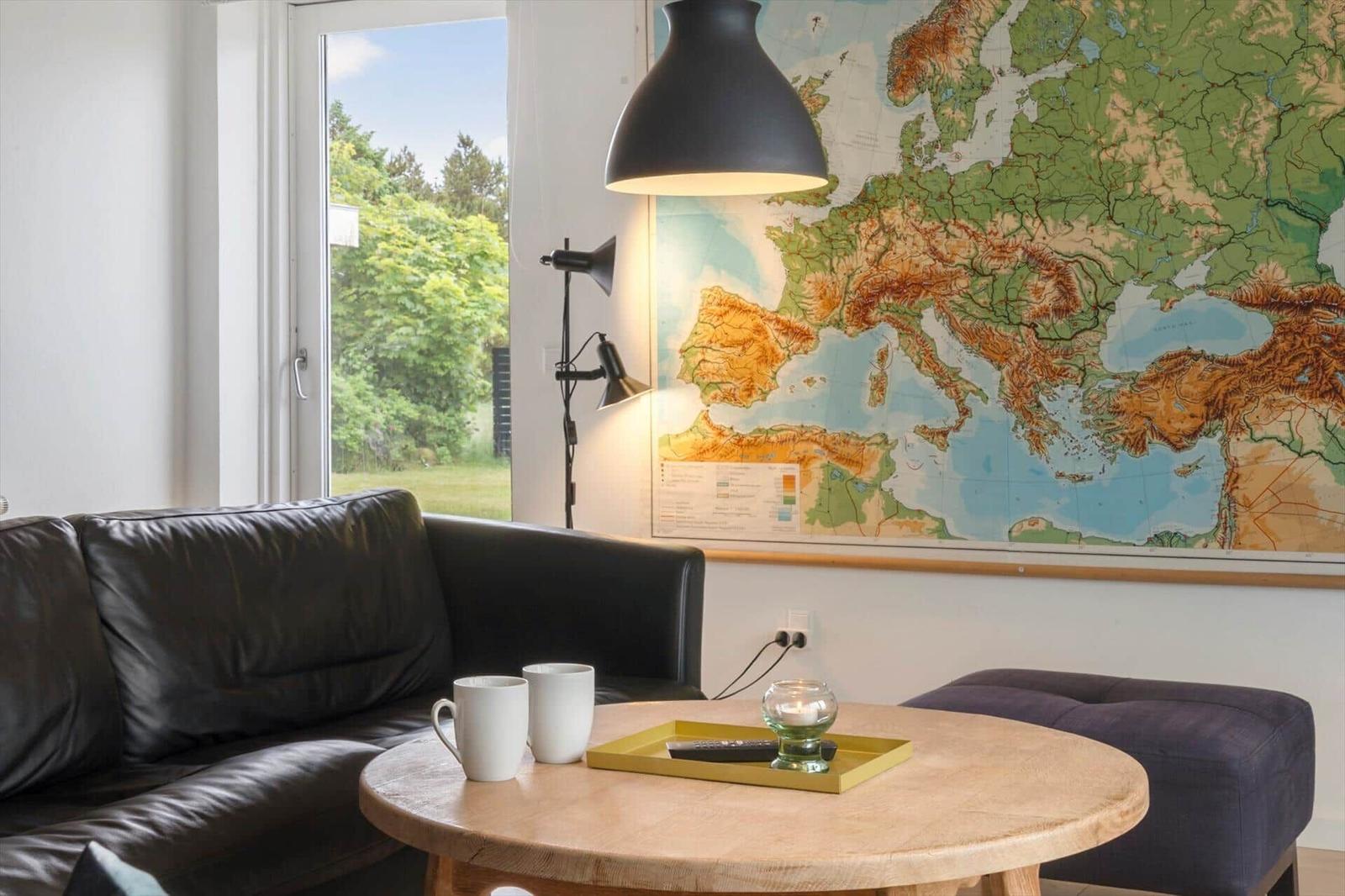 A living room with sofa, table, and map on the wall.