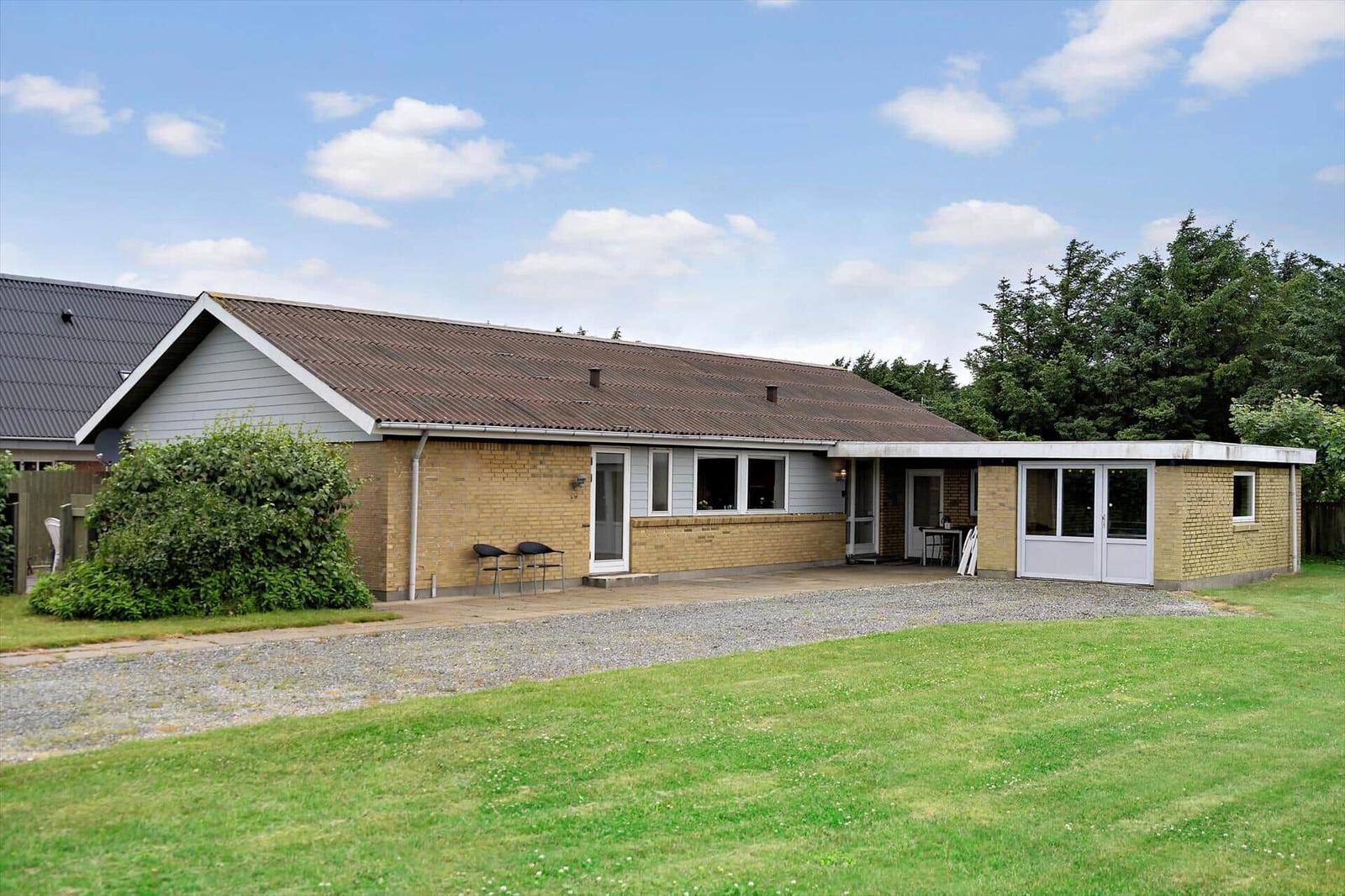 A modern house with stone wall and terrace outside.