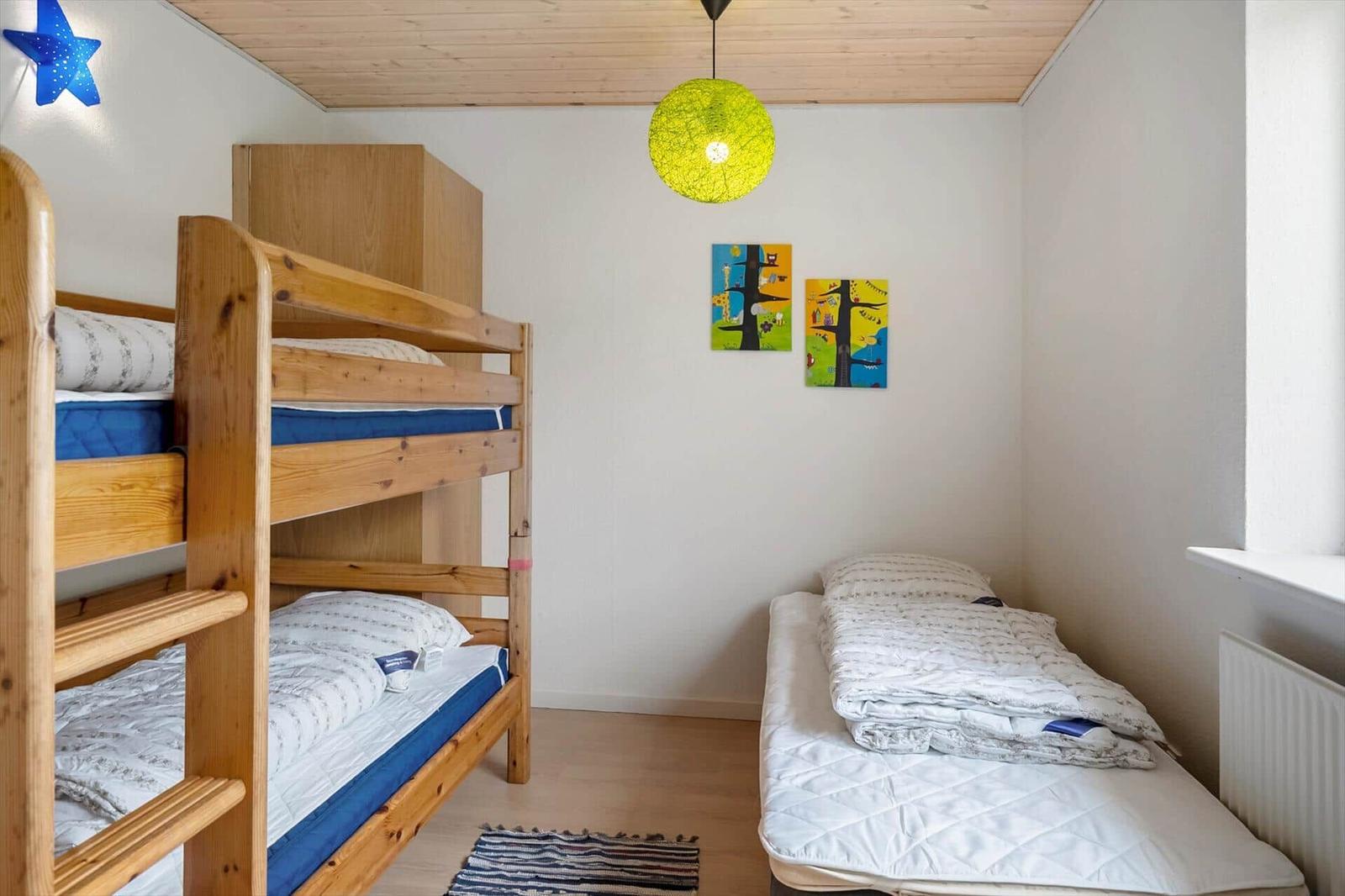 Room with wooden bed, mattress, wall art, and quilt.