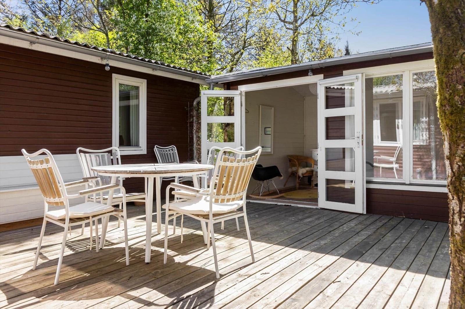 Deck with table and chairs, access to house through glass doors.