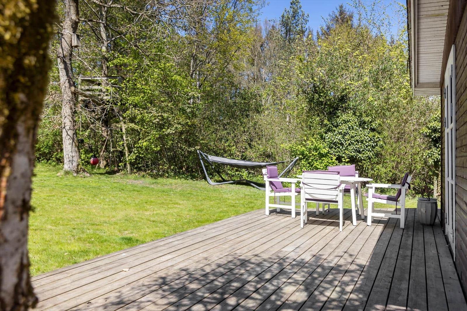 Deck with table, chairs, and hammock setup in the green.