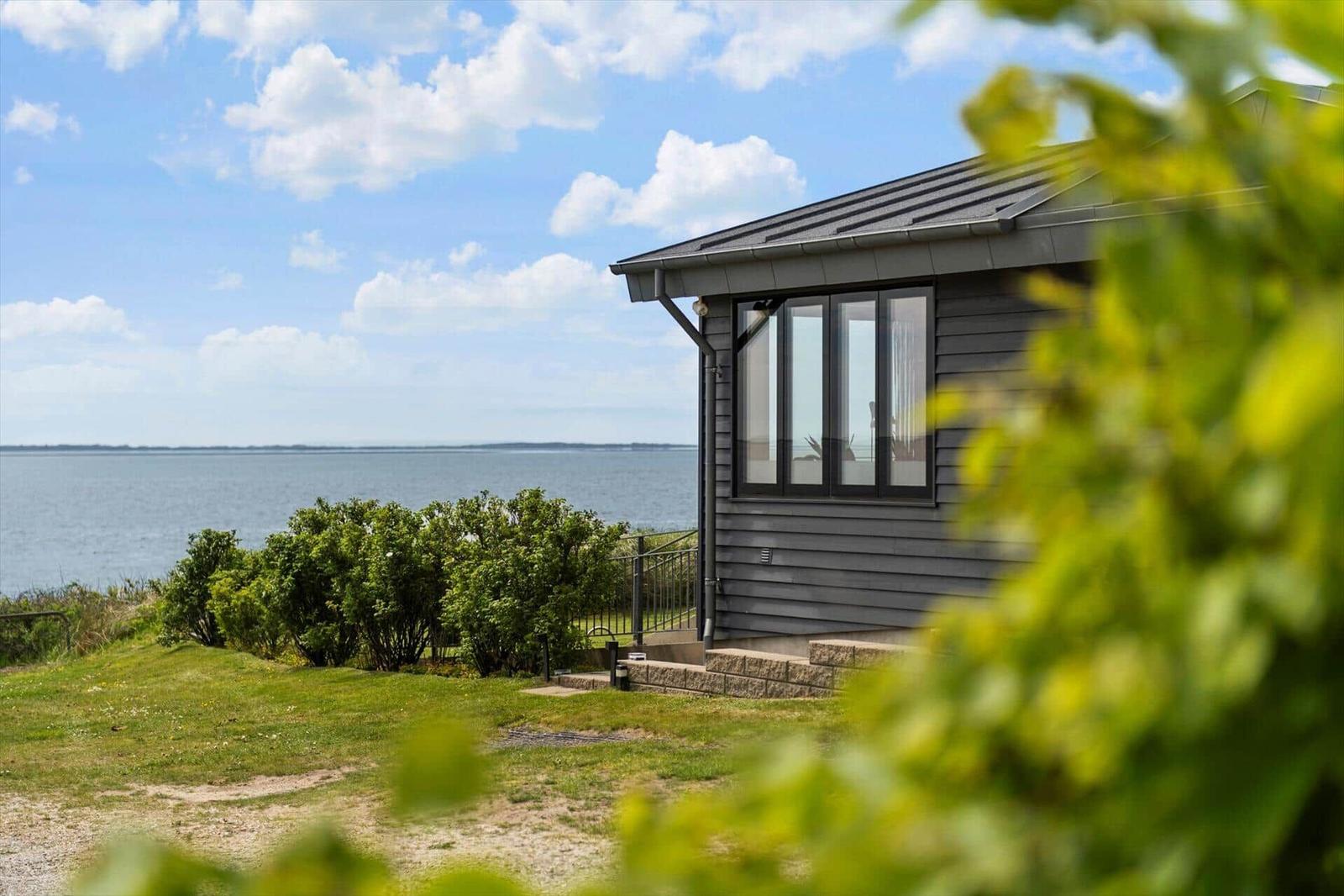 Moderne Strandhaus mit großem Fenster und Blick auf das Wasser.