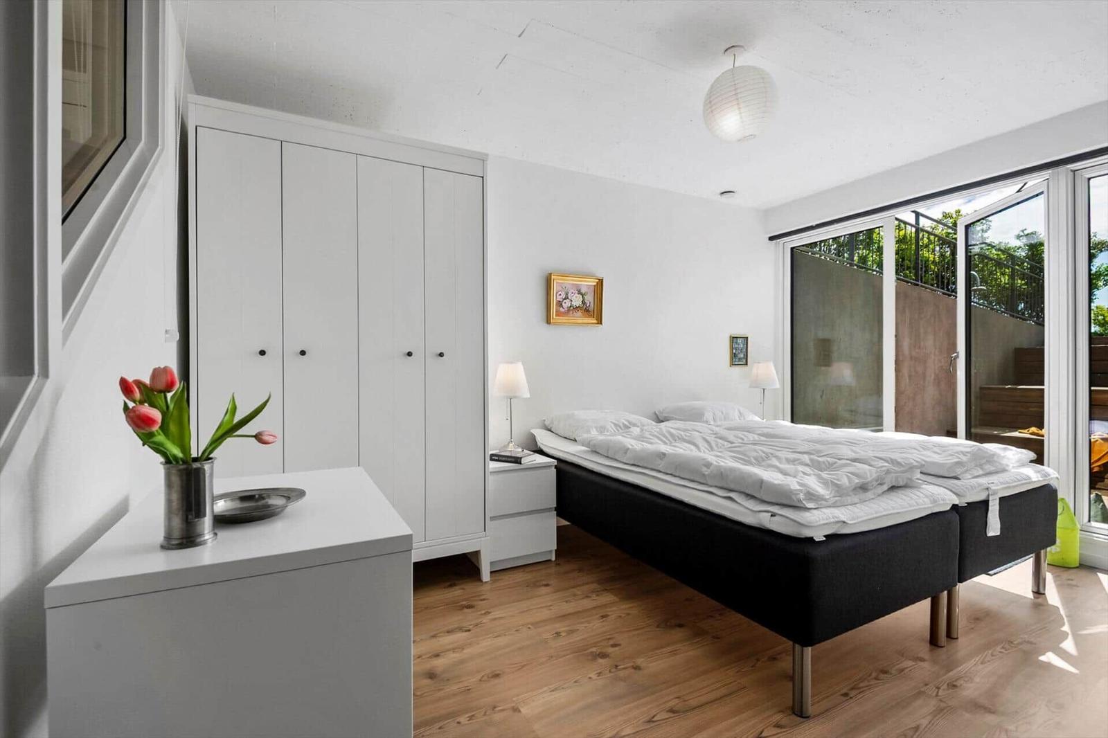 Schlafzimmer mit Doppelbett, Schrank und Fenster zur Terrasse.