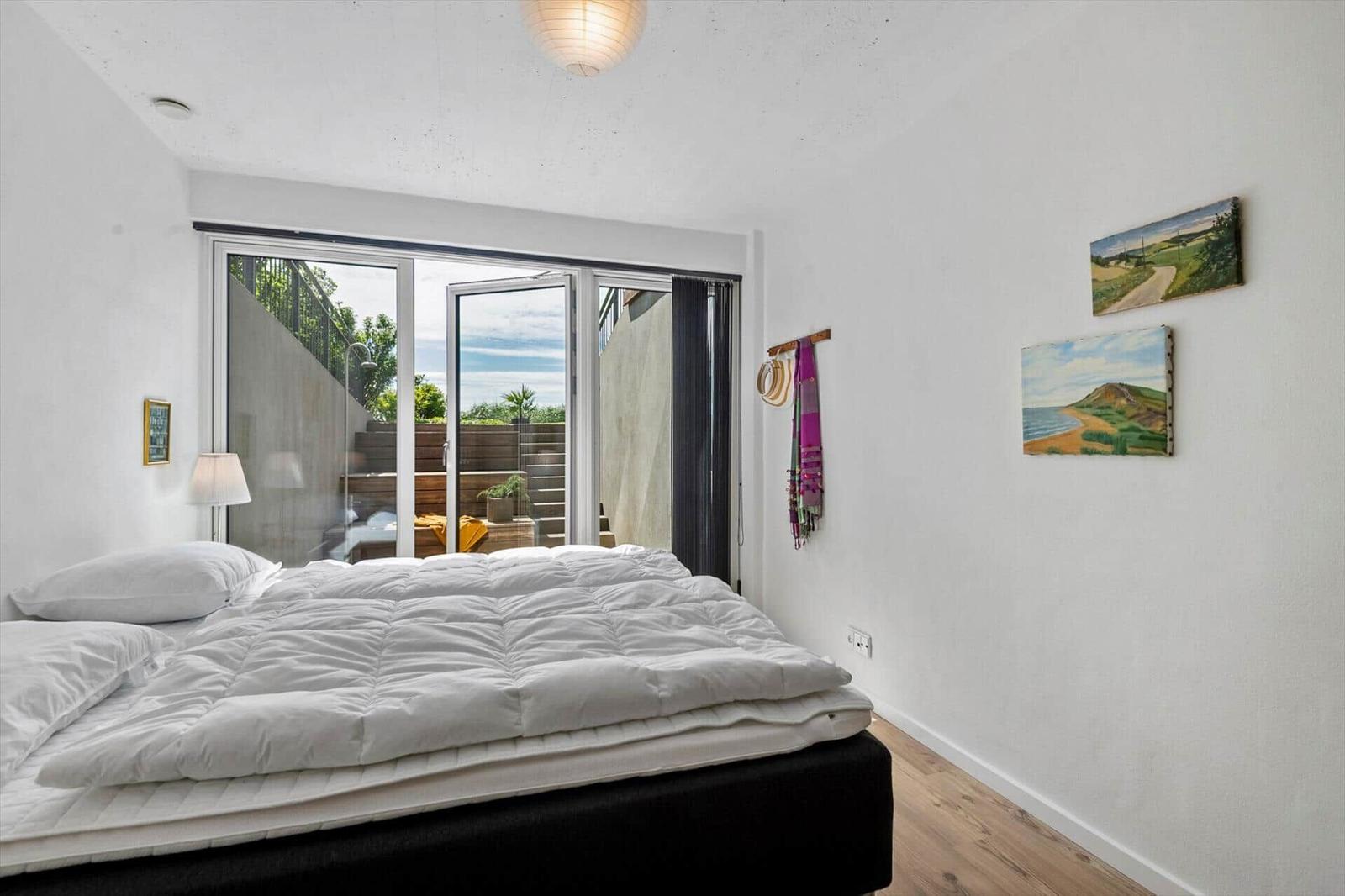 Schlafzimmer mit Bett, Fenster und Wandbildern.