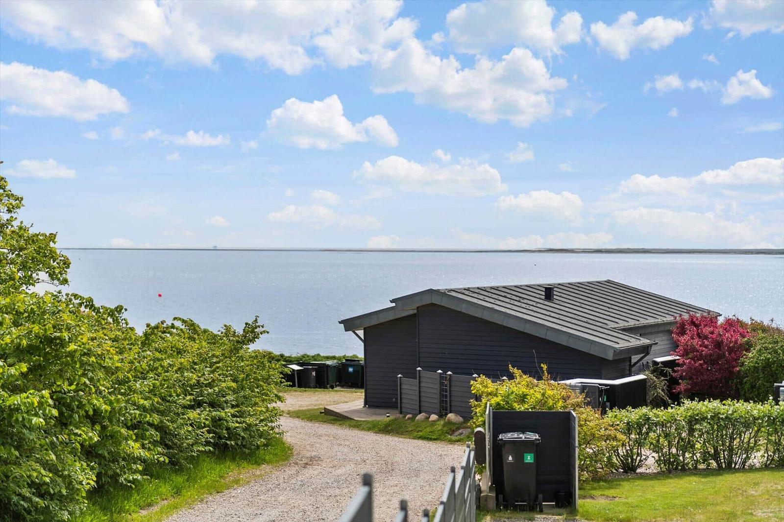 Ein modernes Haus mit Blick auf das Meer und grüne Vegetation im Vordergrund.