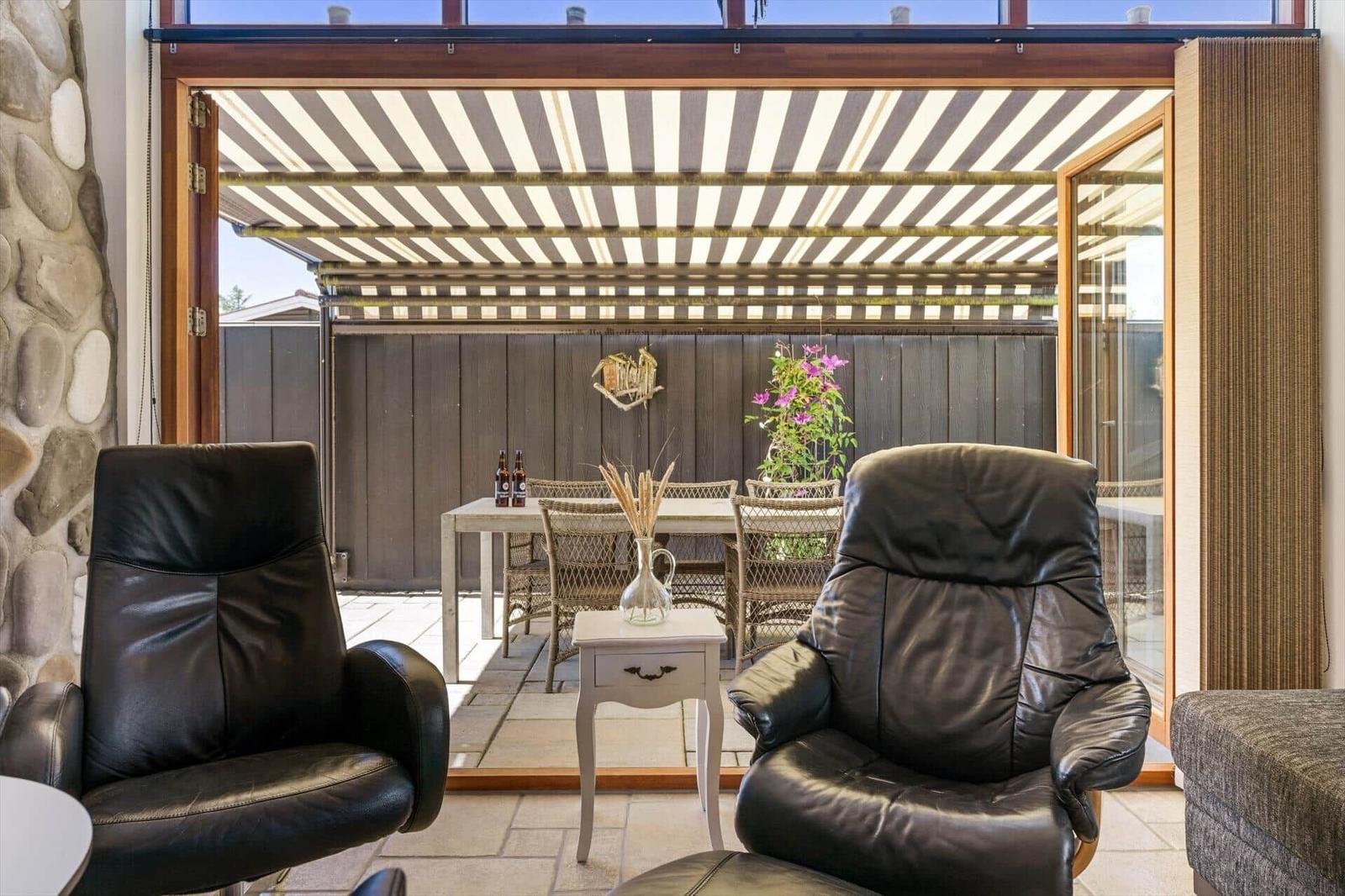 Two black leather chairs face a glass door to an outdoor area with a table and chairs.