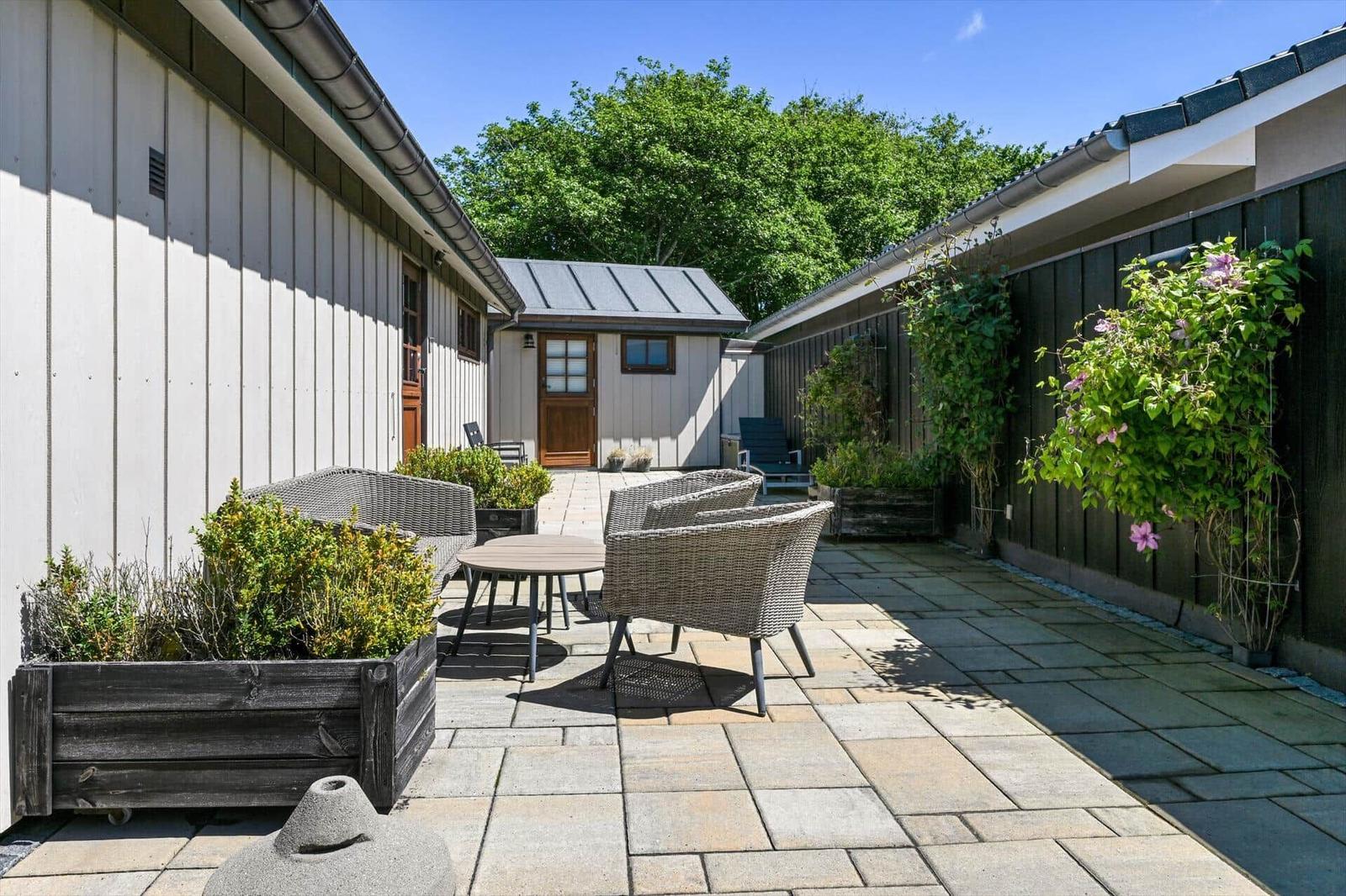 Garden with seating, plants, and stone pavers between buildings.
