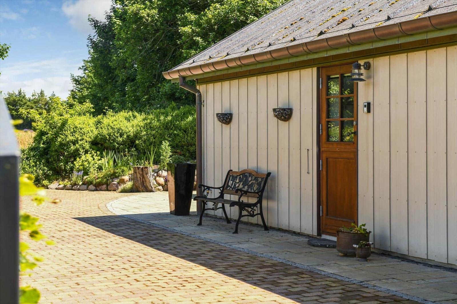House with wooden door, bench, and paved path in the garden
