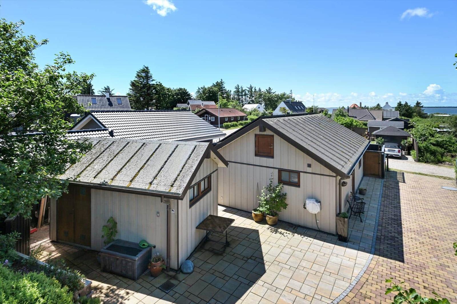House with terrace, plants, and garage. View of residential area and water.