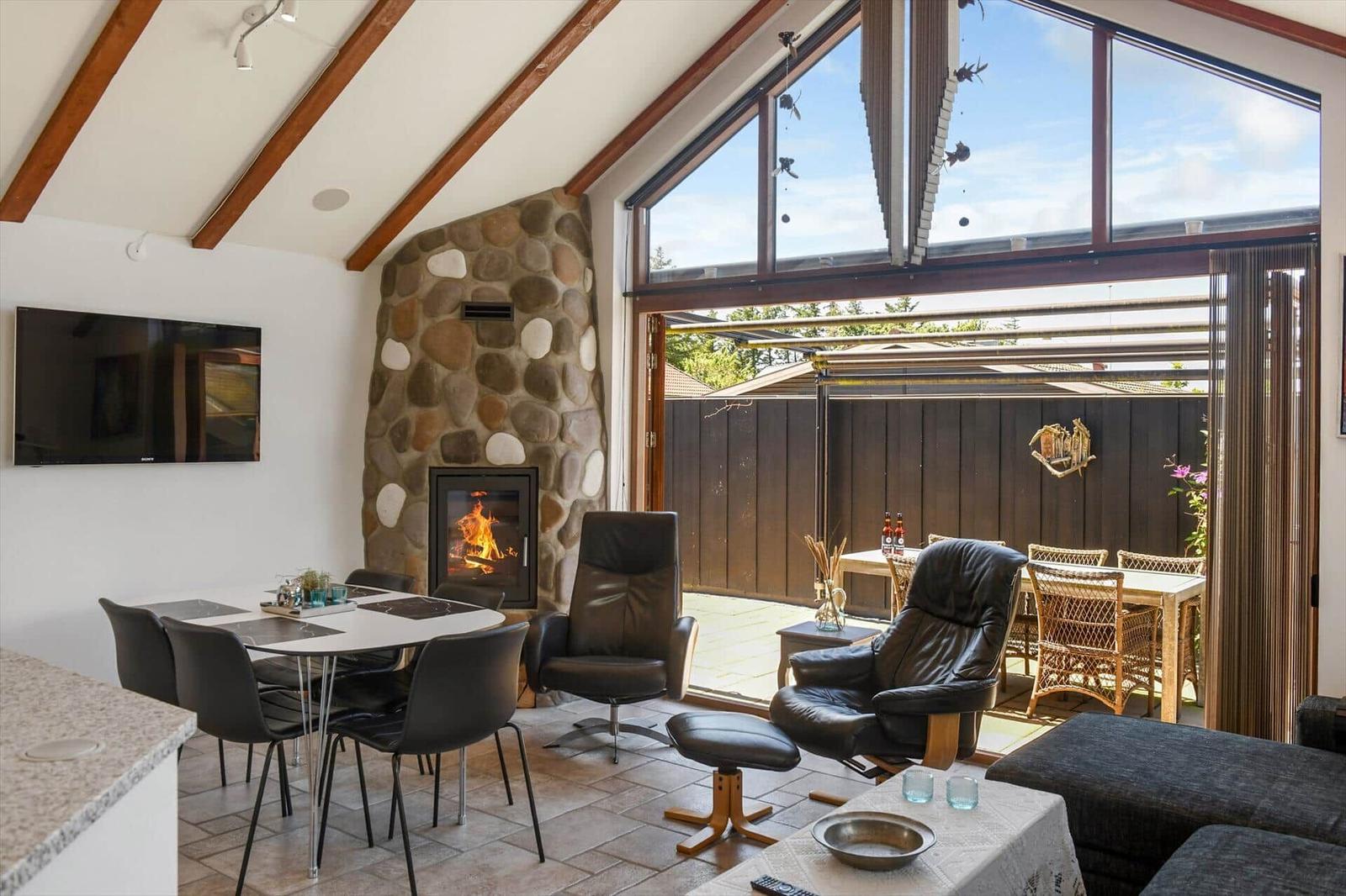 Living area with fireplace, dining table, and view of the terrace.