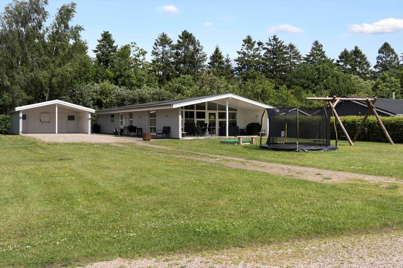 Modern vacation home with large garden, trampoline, and grill area.