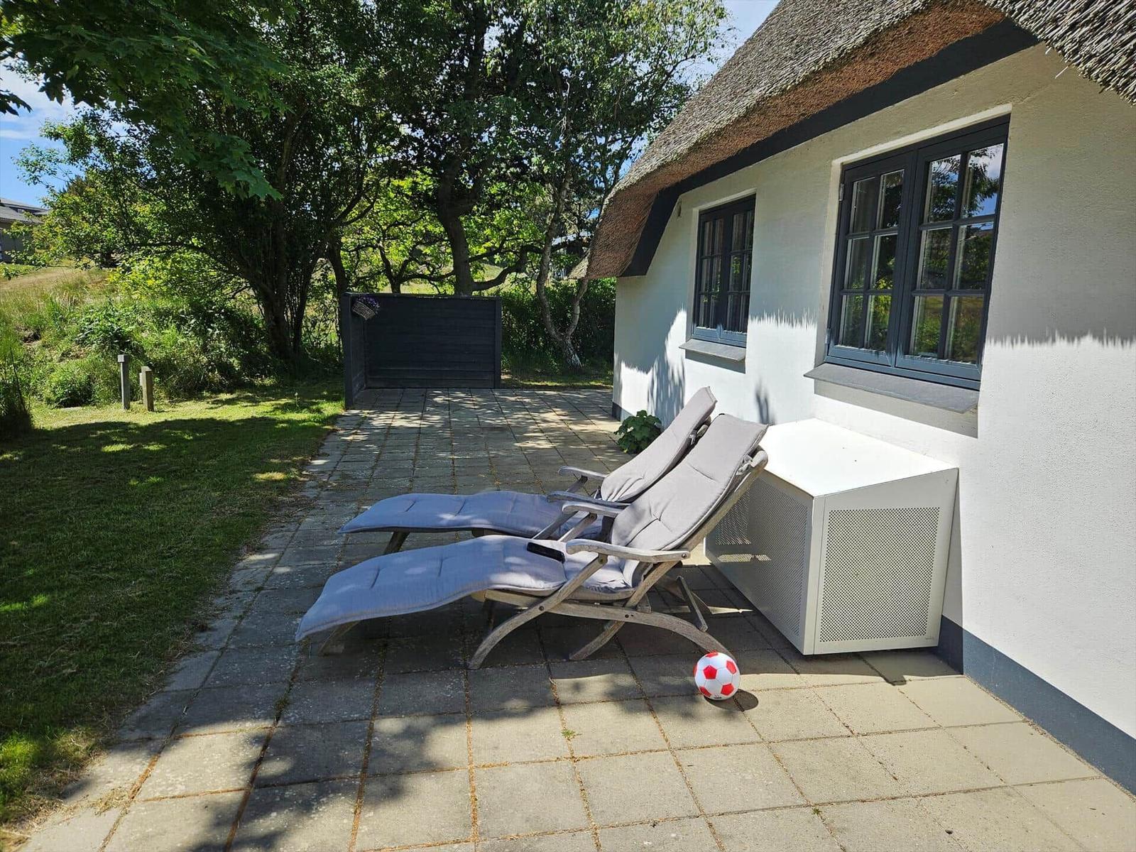 Hinterhof mit Liegestühlen, Fußball und weißem Kasten an Hauswand.