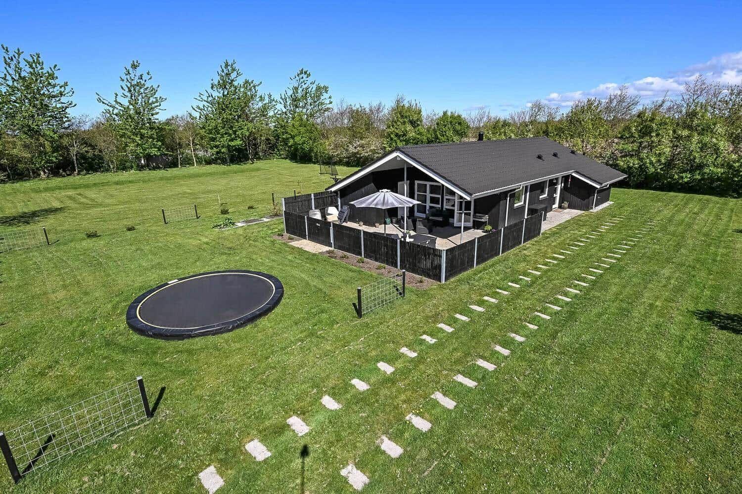 Haus mit großem Garten, Trampolin und Terrasse mit Sonnenschutz.