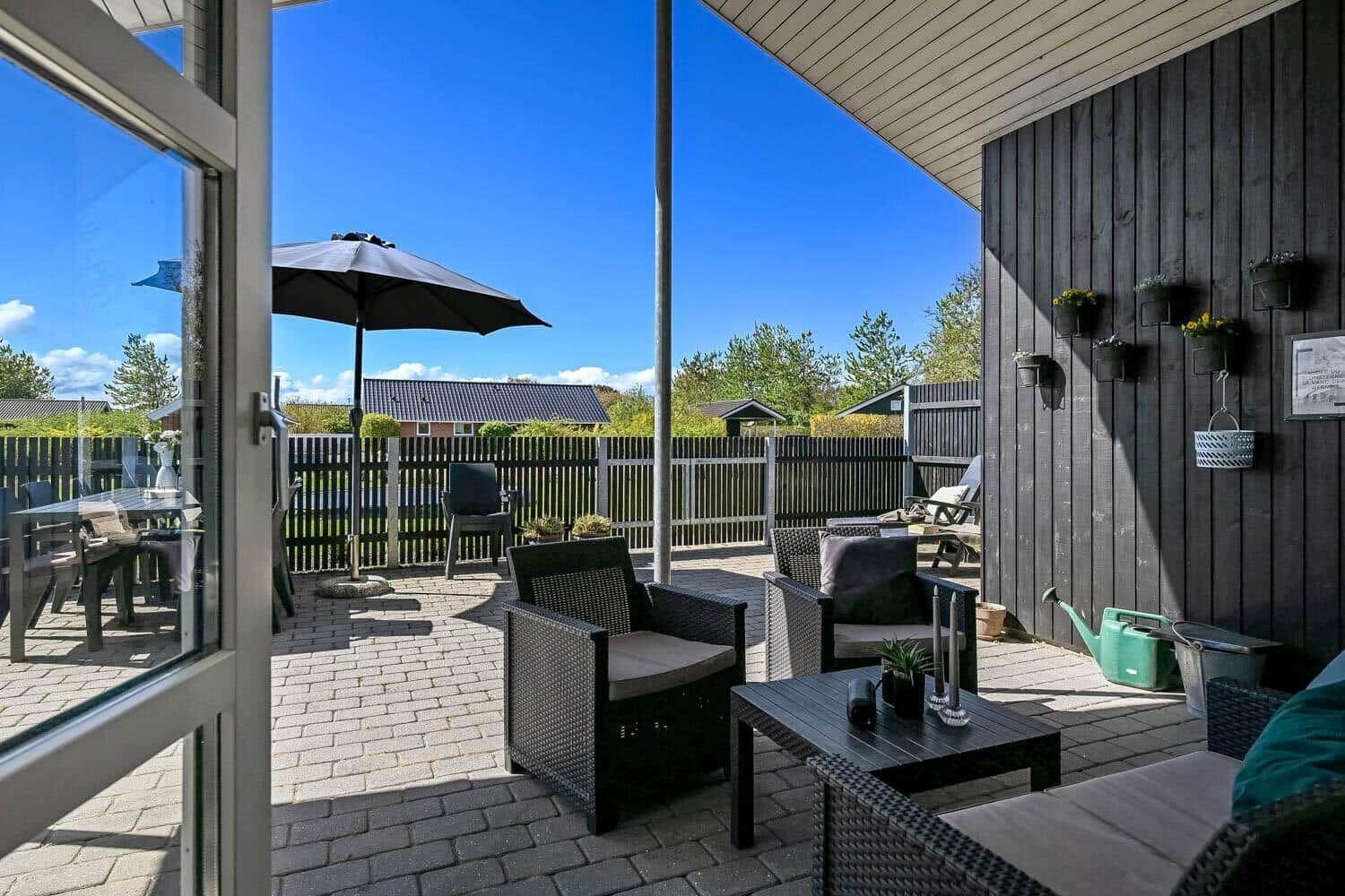 Terrasse mit Sitzgruppe, Sonnenschutz und Pflanzen an der Wand.